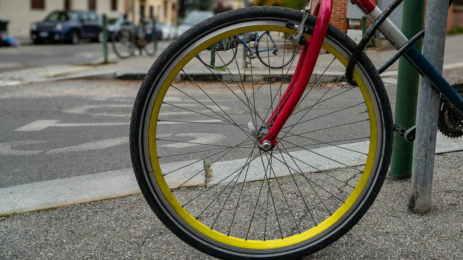Κόκκινο ποδήλατο δεμένο με κλειδαριά σε κολόνα του δρόμου.